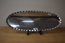 A L.R.T Borrowdale stainless steel dish tray having hand beaten edge, supported on three legs,