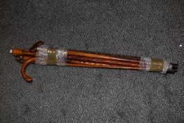A group of five mixed walking sticks/canes, to include rootwood example and two with carved spiral