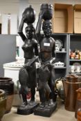 A pair of carved hard wood African tribal sculptures each carrying fish and vessels, h69cm