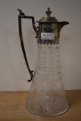 A clear glass and silver plate claret jug decorated with engraved foliage patterns and part