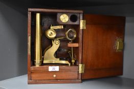 An early 20th century brass microscope having magnifying glass and slides, fitted within a