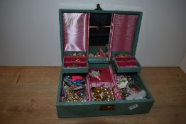 A green faux leather musical jewellery box, containing an assortment of costume jewellery