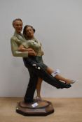 An Art Deco plaster figure of a dancing couple, both wearing gold lustre jackets, supported on a