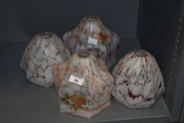 A group of four mid-20th century mottled glass lamp shades, two with floral transfer decoration