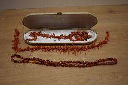 An amber bead necklace with screw-clasp, 60cm open, sold along with two stained coral bead necklaces