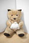 A modern Teddy Bear seated holding a Sugar Bag, height 45cm