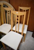 A modern beech effect circular dining table with extension leaves, and four similar dining chairs