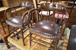 A pair of early 20th Century oak spindle back of armchairs having overstuffed studded leather seats