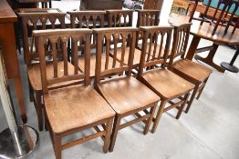 A set of eight oak Arts and Crafts solid seat chapel or hall chairs in the Gothic style