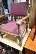 An early 20th Century oak framed low seat armchair having moquette upholstered seat and back