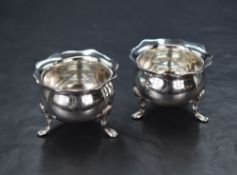 A pair of Edwardian silver salts, of bulbous form having Chippendale style rim, raised on three