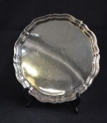 A George V silver salver, of circular form having a Chippendale style rim raised on three scroll