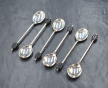 A cased set of six George V silver coffee bean spoons, having black coffee beans to the terminals,