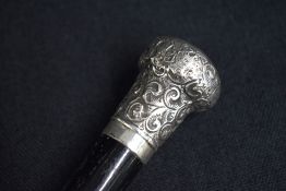 A George V silver mounted walking stick, the repousse pommel having decorative scroll decoration