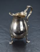 A George V silver cream jug, having a Chippendale style rim with a generous flat spout, opposed by a