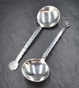 A cased pair of George V silver serving spoons, having a Chippendale style edge with a pelican