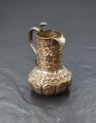 An Eastern white metal cream jug, of bulbous form having a narrow spout opposed by a handle in the