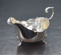 A George V silver sauce boat, having a Chippendale style rim and generous spout opposed by a s-curve