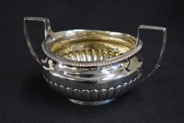 A George III silver sugar bowl, of traditional form having an egg and dart rim and half gadrooned