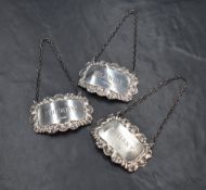 Three Elizabeth II silver decanter labels, of rectangular form having scroll and shell borders for