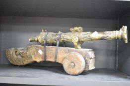 A late 19th / early 20th century cast brass table top cannon, mounted on a wooden wheeled