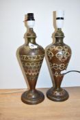 A near pair of brass lamps decorated with floral enamel patterns of blue, yellow and red colour,