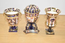 A Royal Crown Derby three legged lidded urn in the Imari pattern, makers mark to base, date code for