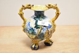 A Majolica style vase decorated with multiple colour glazes and fish form handles, supported on