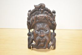 An early 20th century Chinese Empire face mask hand carved with dragons and having bone eyes, h16cm