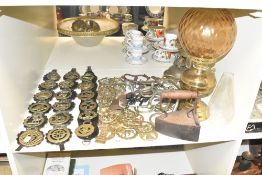 A large group of horse brass, sold together with a brick float iron, two vintage oil lamps and glass
