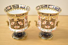 A pair of Royal Crown Derby Imari twin-handled pedestal urns, makers mark to base, pattern 1261,