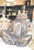 A large patinated metal Buddha in traditional dress, crossed leg and in sitting position, h38cm