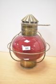 A 20th century brass and glass nautical oil lantern of onion form having hanger and a red glass