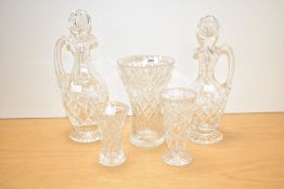 A small group of cut crystal glass comprising two decanters and three vases, one being footed.