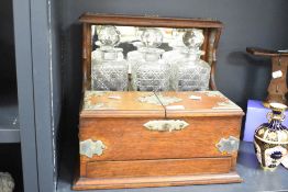 A 19th century tantalus having triple cut crystal decanters housed within a oak case with original