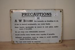 A 20th century enamel sign reading 'precations A W Bombs' having black text on a white ground,