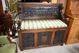 A 19th Century carved oak monks bench, heavily carved including dragons, monogram EC and 1899