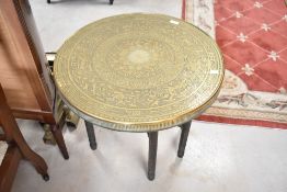 An Indian style brass top table having circular top folding frame, diameter 60cm