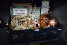 A vintage blue suitcase containing a reproduction copper casserole dish, a set of cased fish