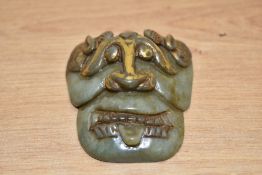 A Chinese carved and gilt embellished greenstone belt buckle, formed as a Hannya style mask, 8cm