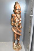 A large African carved hardwood figure of a tribesman grasping a snake which is coiled around his