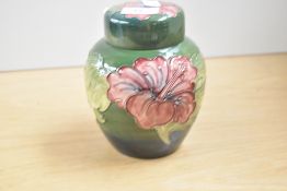 A Moorcroft pottery Hibiscus pattern ginger jar tube lined with foliage against a green ground,