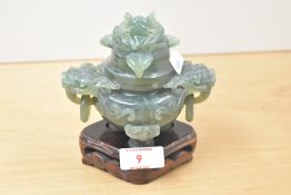 A Chinese green stone lidded censor with Foo dog mask handles supported on a carved wooden stand,