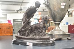 A heavy cast patinated metal sculpture of a Hunter and his dog, mounted on a black marble base,
