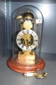 A 20th century German brass and clear glass skeleton mantel clock, with turned wooden base, complete