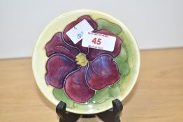 A Moorcroft pottery Hibiscus pattern dish decorated with purple flower on a yellow glaze ground,