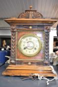An early 20th century mahogany and pinbe cased mantel clock, the finial topped surmount over a