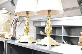 A pair of gilt metal table lamps with woollen shades, supported on a step base and decorated with