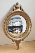 A circular gilt framed convex wall mirror with decorative floral scroll work, 38cm x 23.5cm