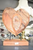 A carved wooden heart shaped sculpture supported on mental pins, h42cm
